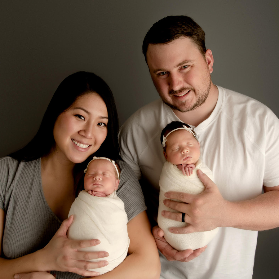A couple is pictured proudly holding their infant children.