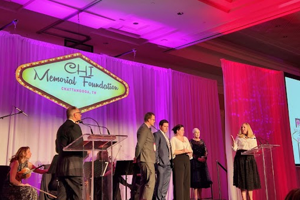 Several people stand on an event stage to receive an award.