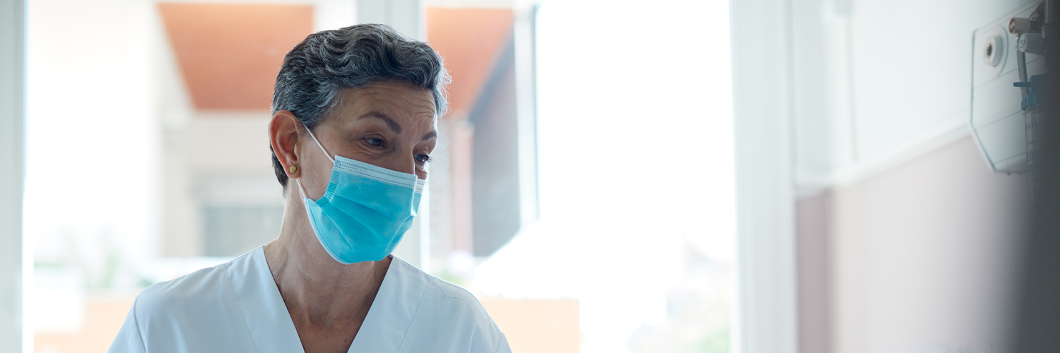 A masked caregiver gazes forward.